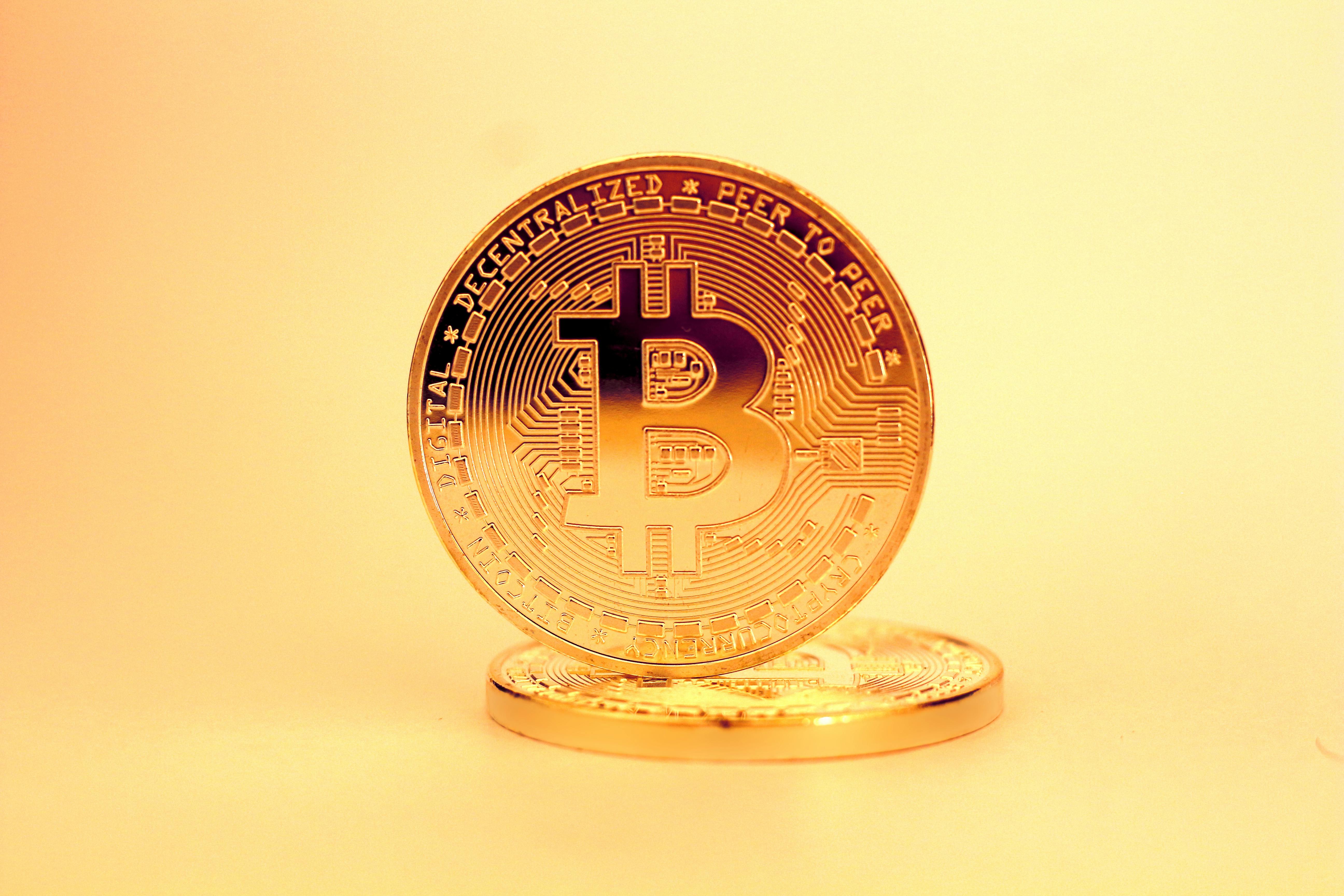Close-up of a gold bitcoin coin on a reflective surface representing digital currency