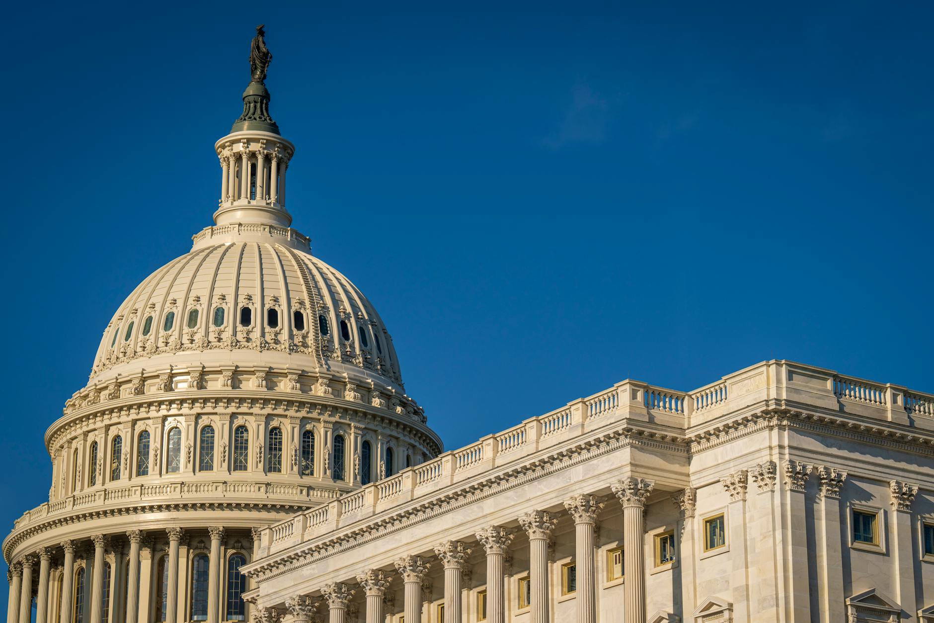 The iconic dome of the United States Capitol against a clear blue sky