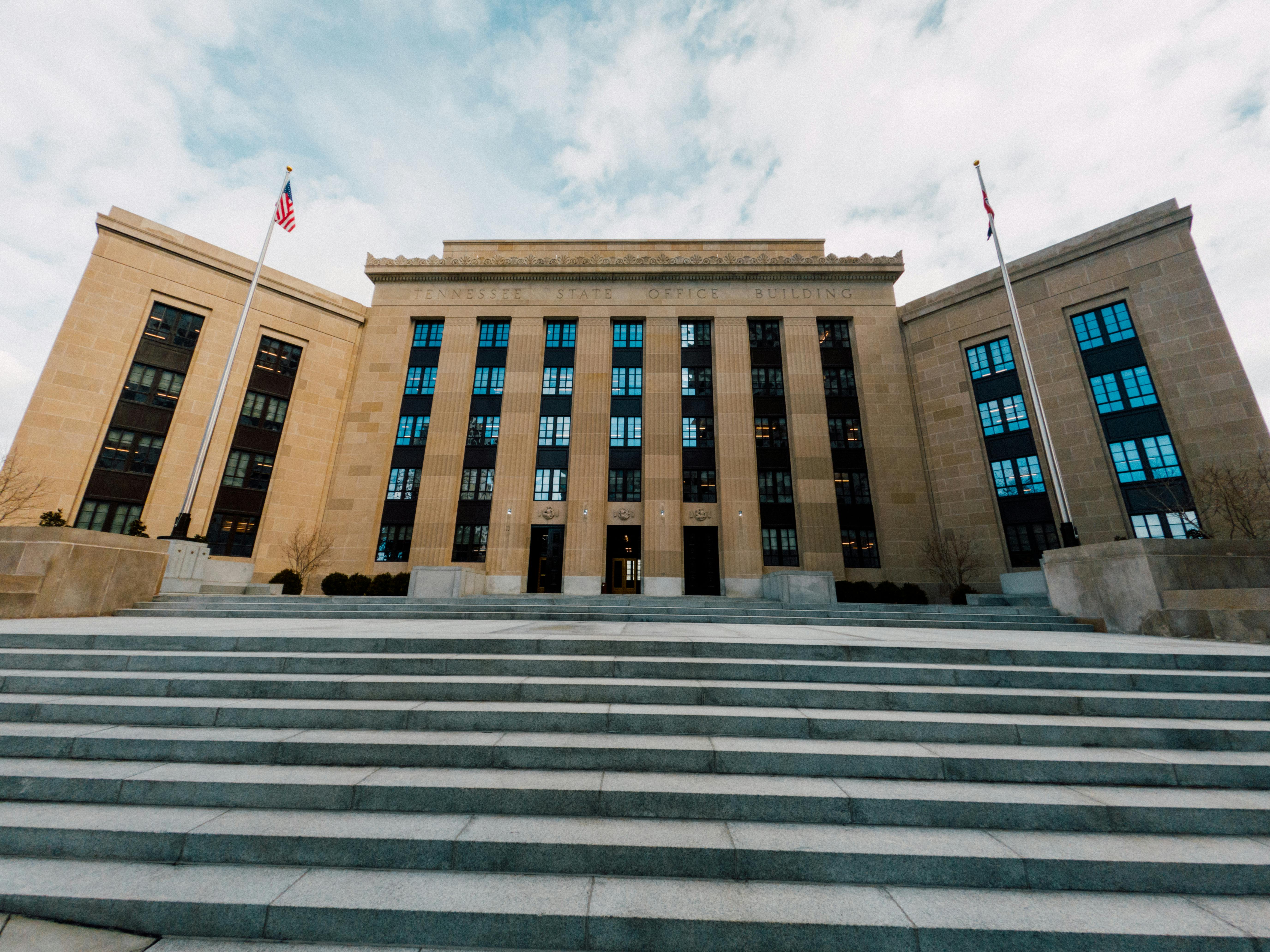 Federal Reserve Building facade in Washington, D.C., with American flags and staircase under cloudy sky