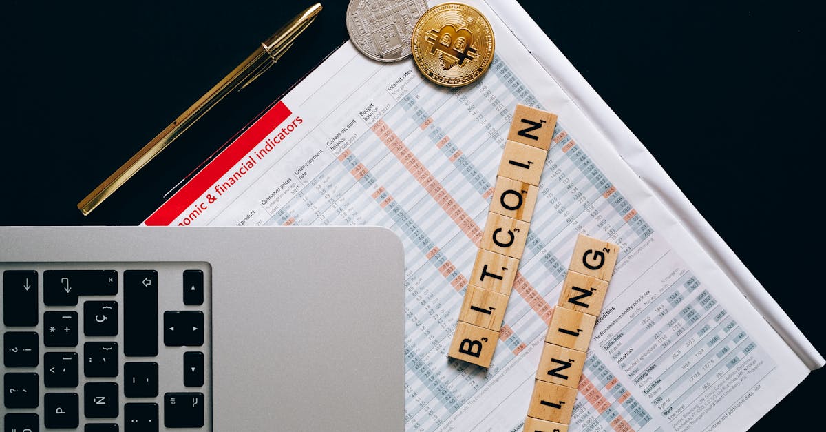 Bitcoin coins on a desk beside a laptop displaying financial charts and trading indicators