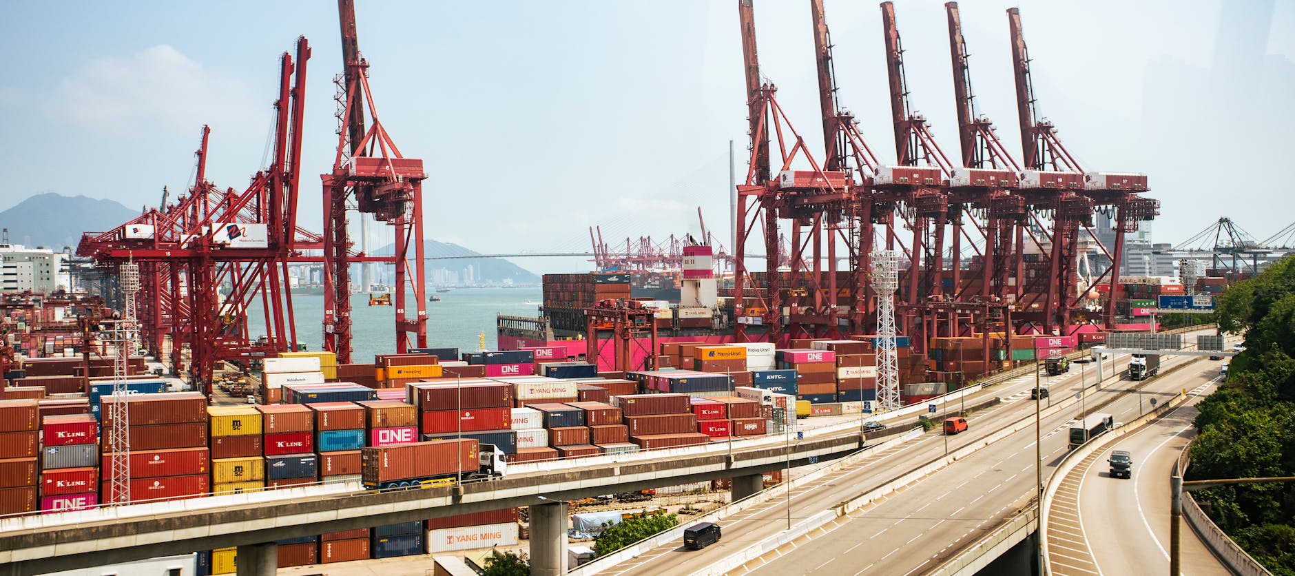 Container ships and red cranes at a Hong Kong port terminal, illustrating China's export trade activity