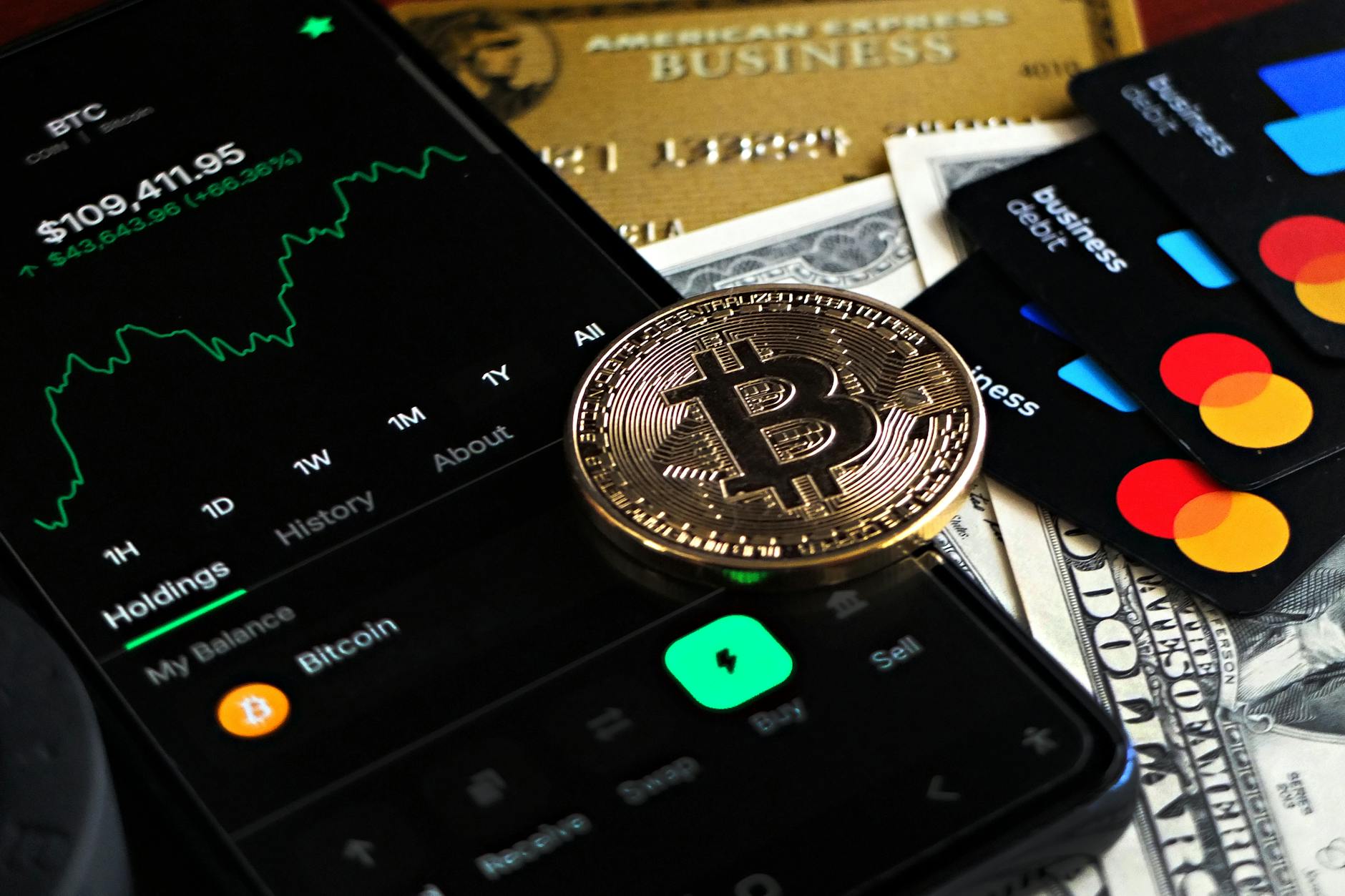 Bitcoin coin with credit cards and financial data on a trading desk, representing the intersection of traditional banking and cryptocurrency