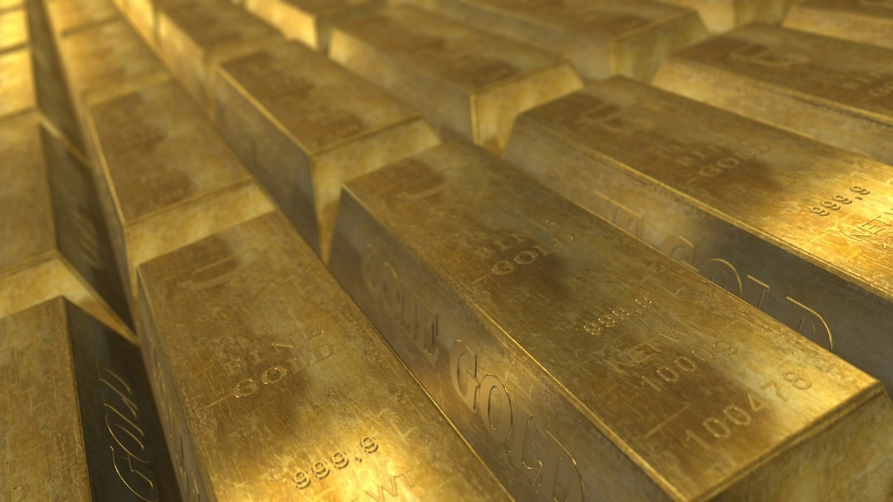 Stacked gold bars on a reflective black surface, representing the commodities segment of tokenized real-world assets