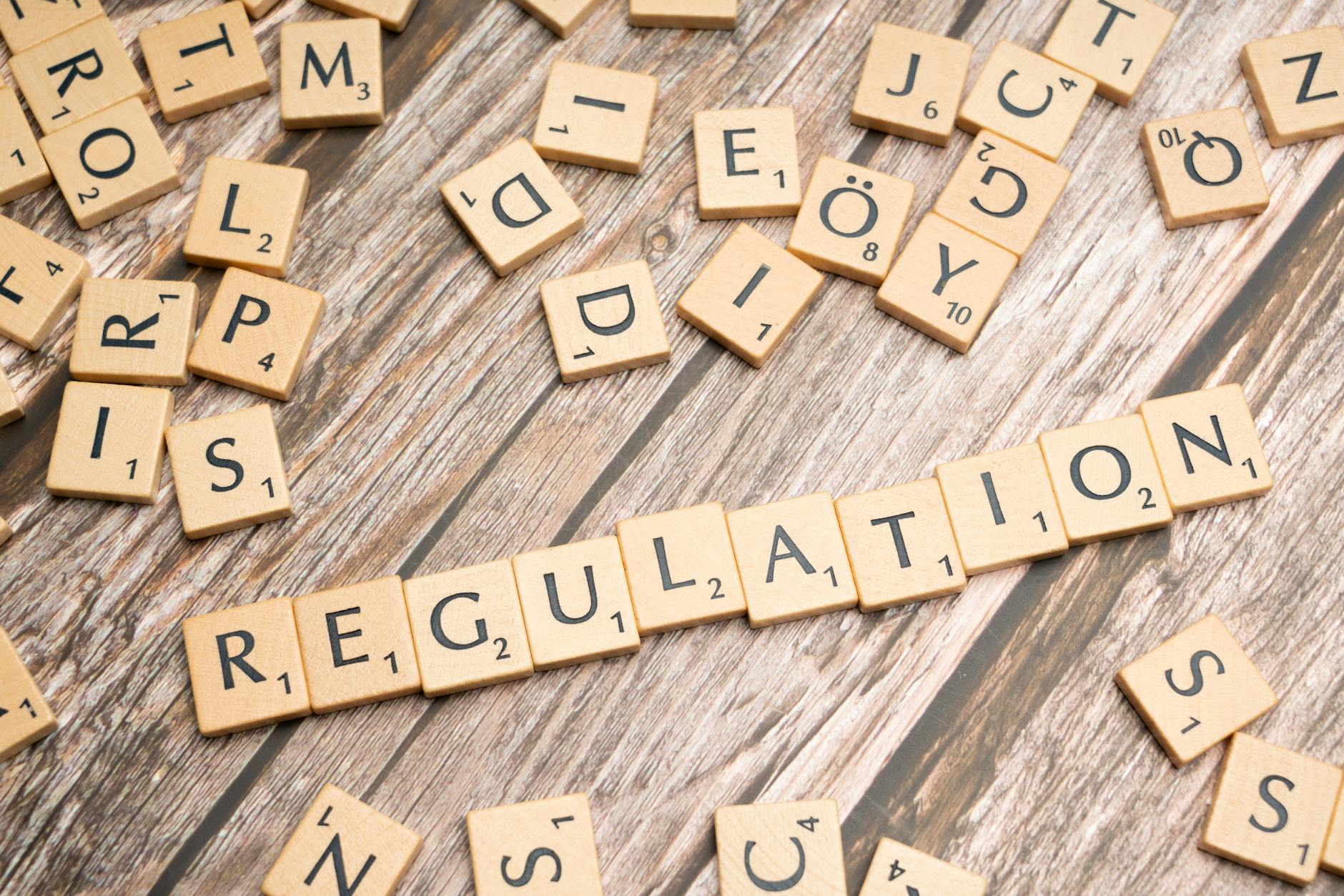 Wooden tiles spelling 'Regulation' on a textured wood background