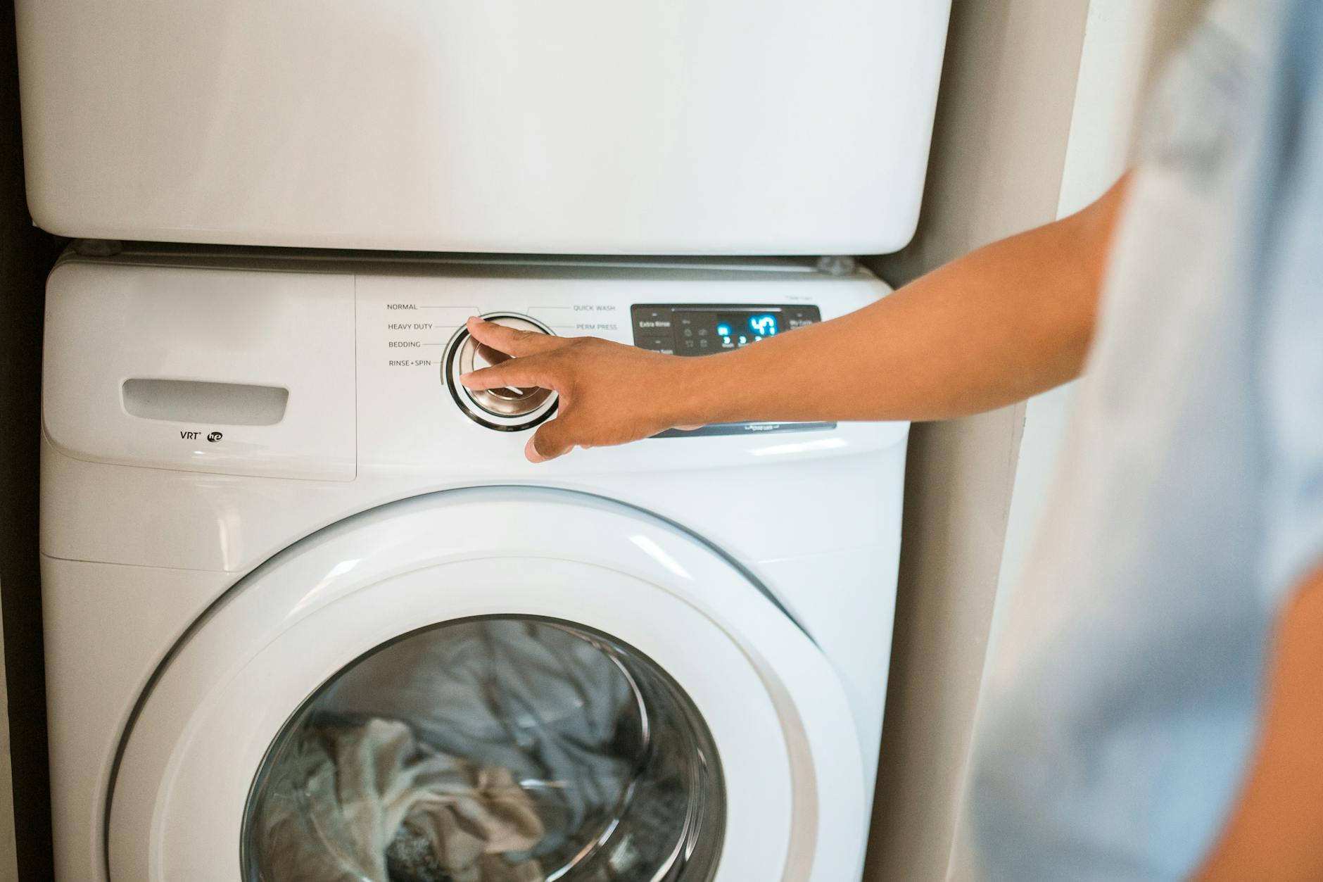 Person operating a front-load washing machine in a residential laundry room