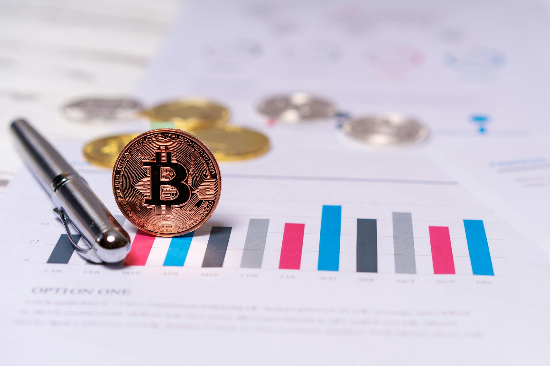 Bitcoin coin resting on a financial chart printout with a black pen, suggesting balance-sheet analysis