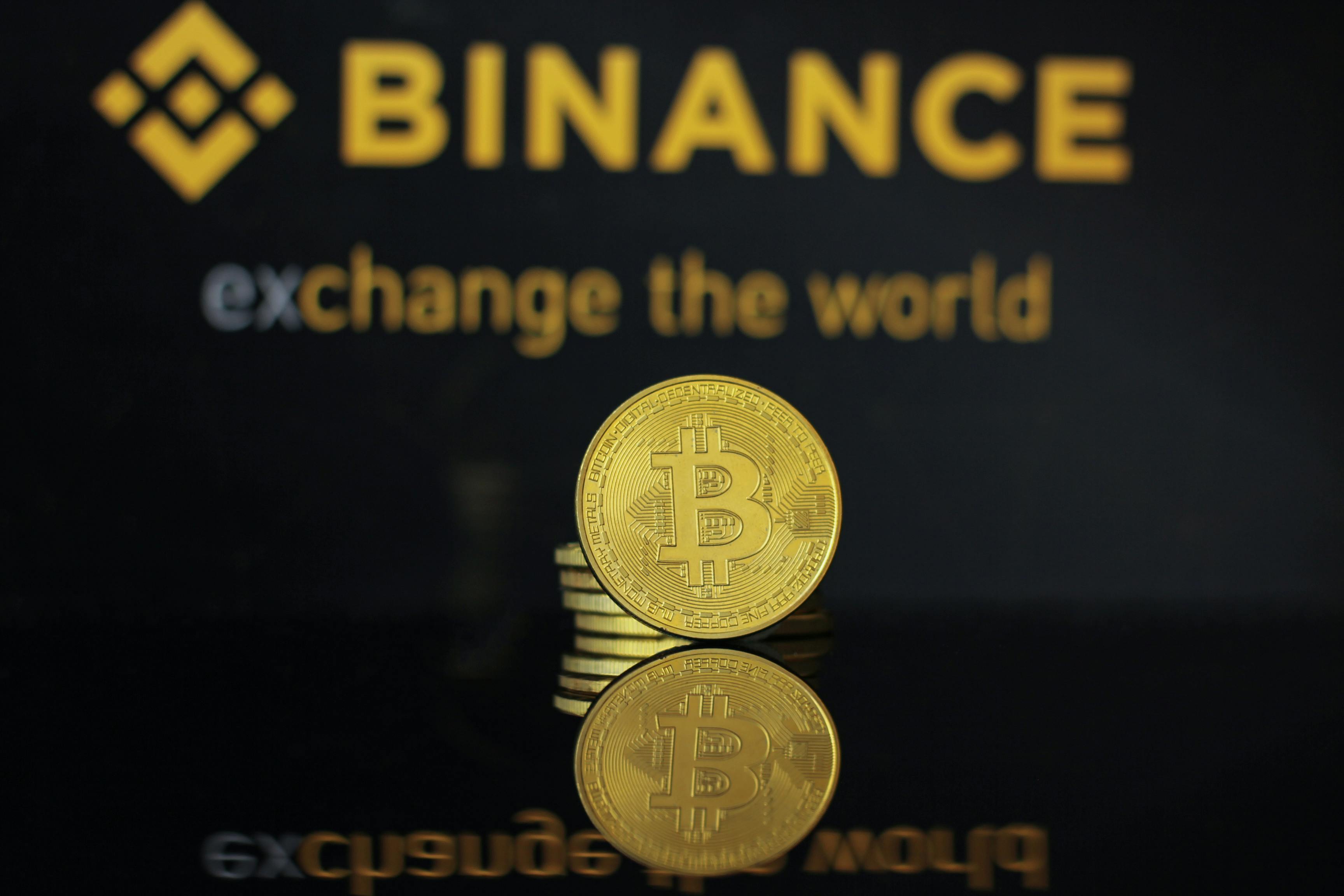 Close-up of a Bitcoin coin with Binance logo reflecting in dark surface