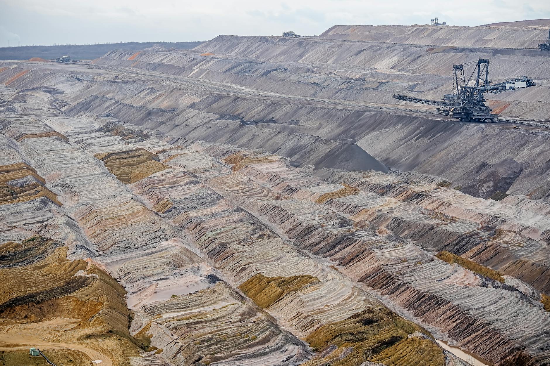 Aerial view of a large open-pit copper mine with industrial machinery and layered excavation terraces