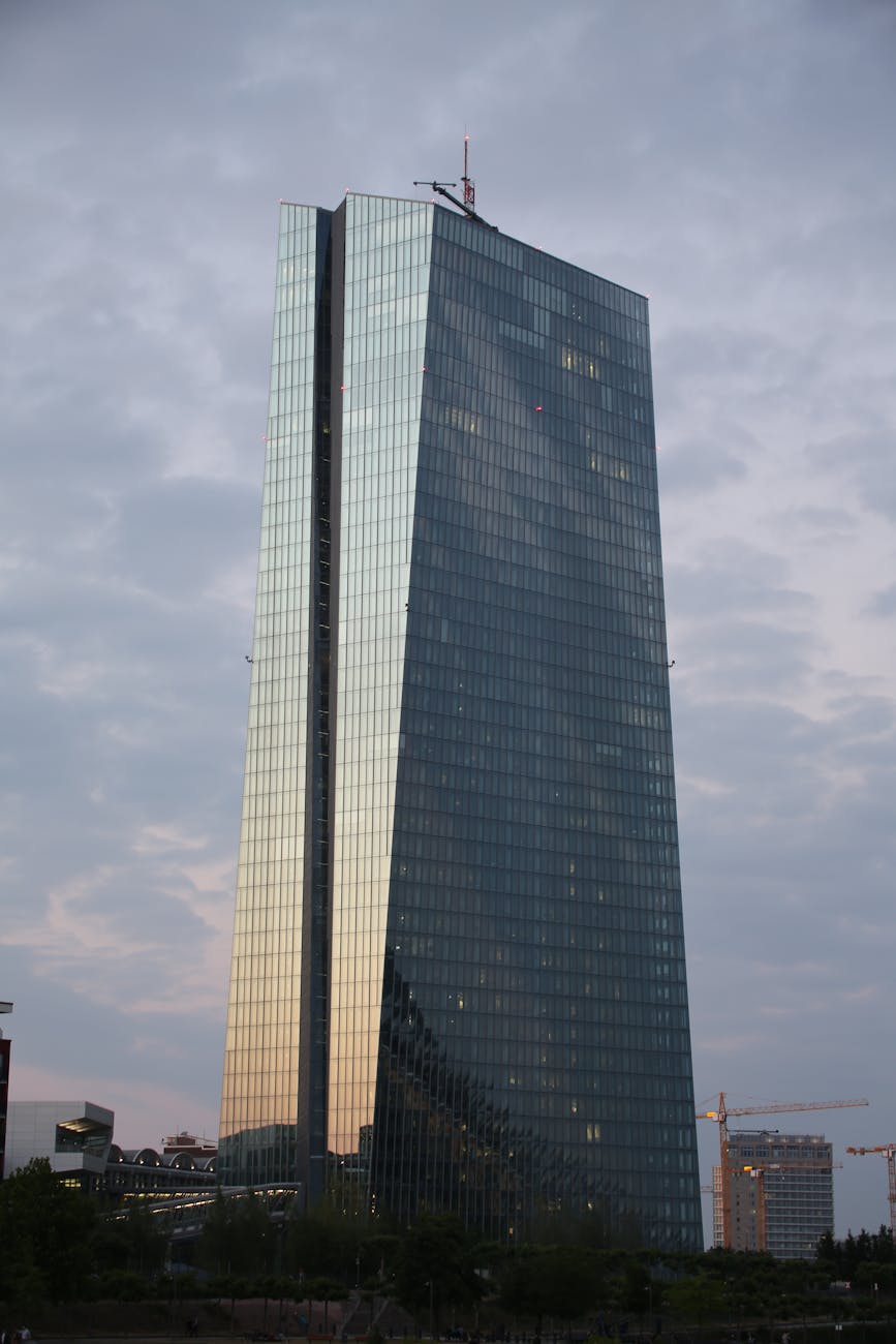 A modern glass skyscraper reflecting the hues of a sunset sky — Frankfurt's financial district