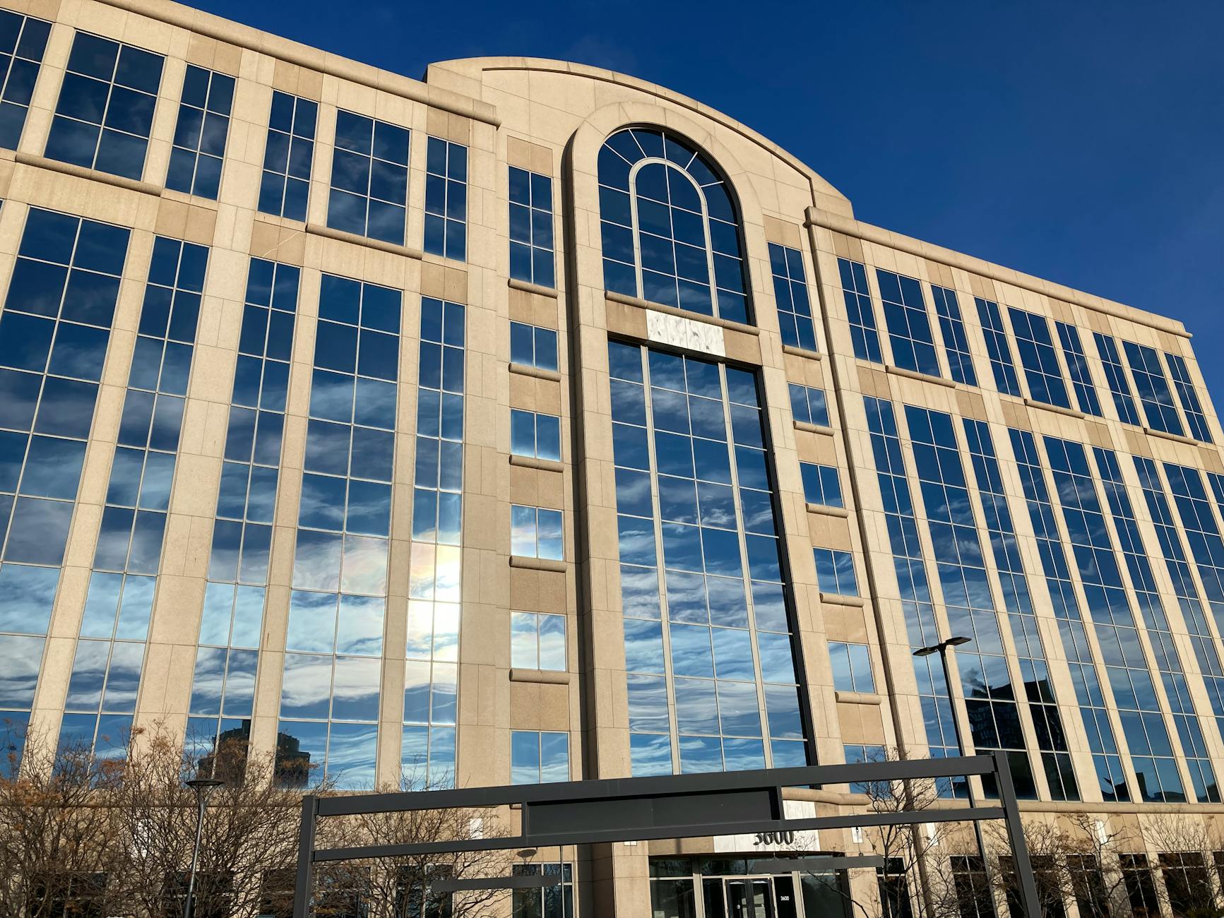 Modern office building with reflective glass facade under a blue sky