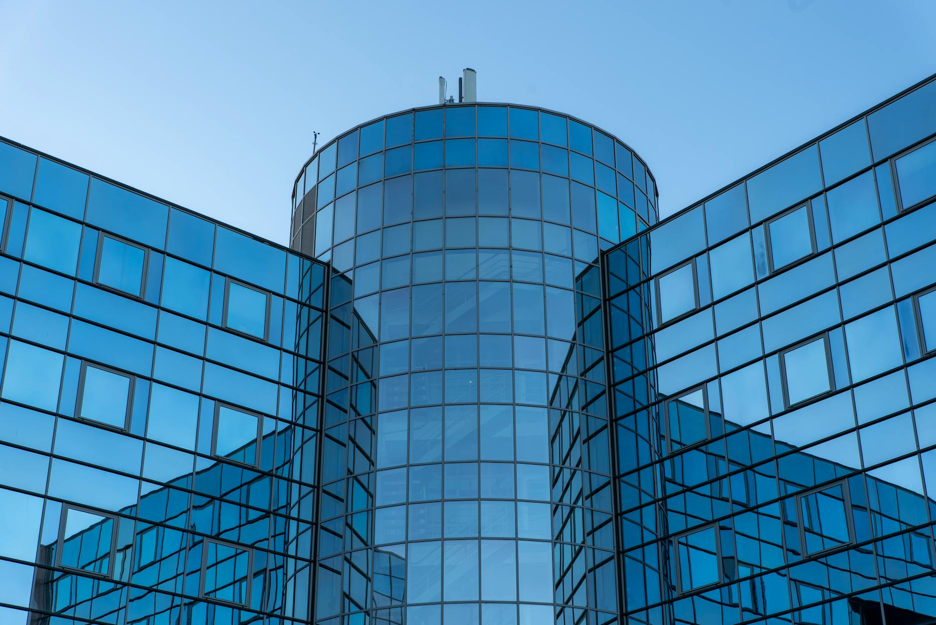 Modern glass facade of urban office building under clear blue sky