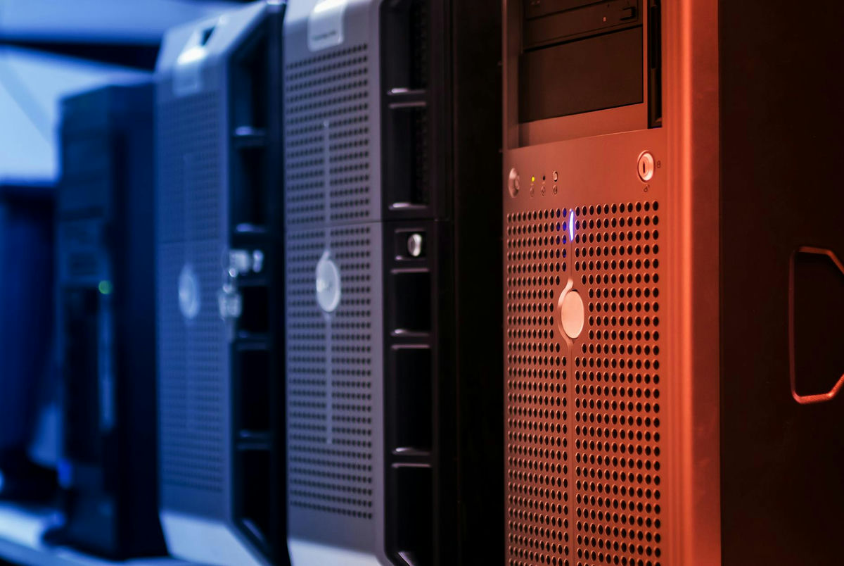 Close-up view of tower servers in a data center with blue and red lighting, echoing the costly infrastructure behind AI listings.