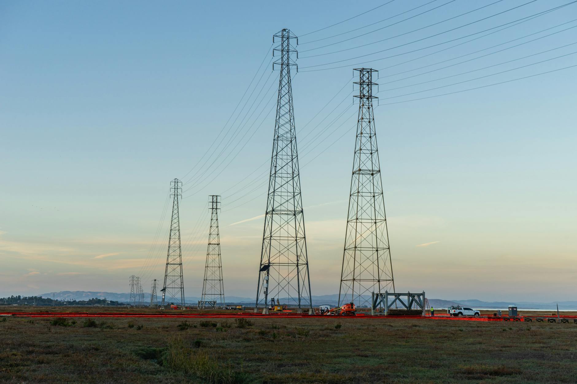 Miniatures of windmill, solar panel and electric pole are seen in front of NextEra Energy logo in this illustration
