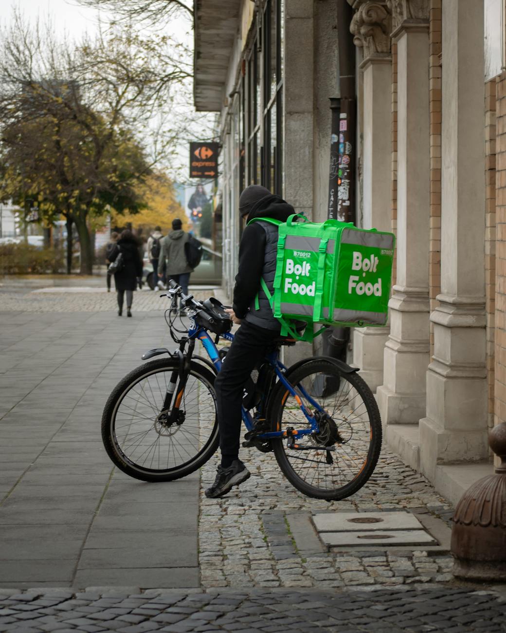Cyclist delivering food on a European city street, illustrating urban food-delivery competition.