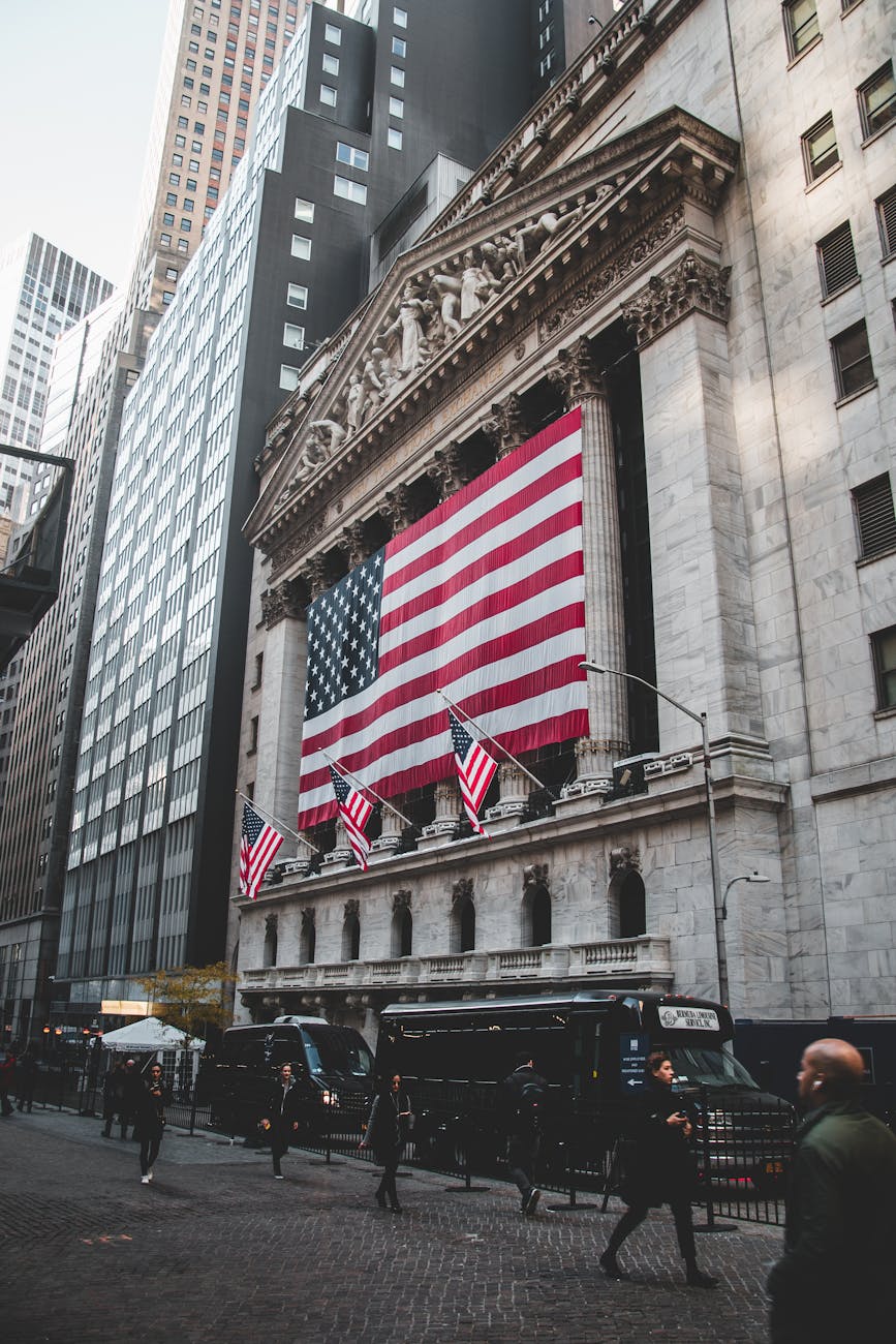 The New York Stock Exchange facade with oversized American flags on Wall Street.