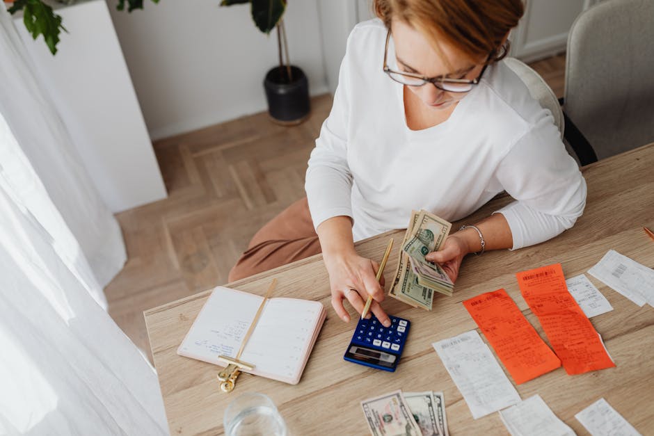 Person managing household bills with a calculator and cash at home