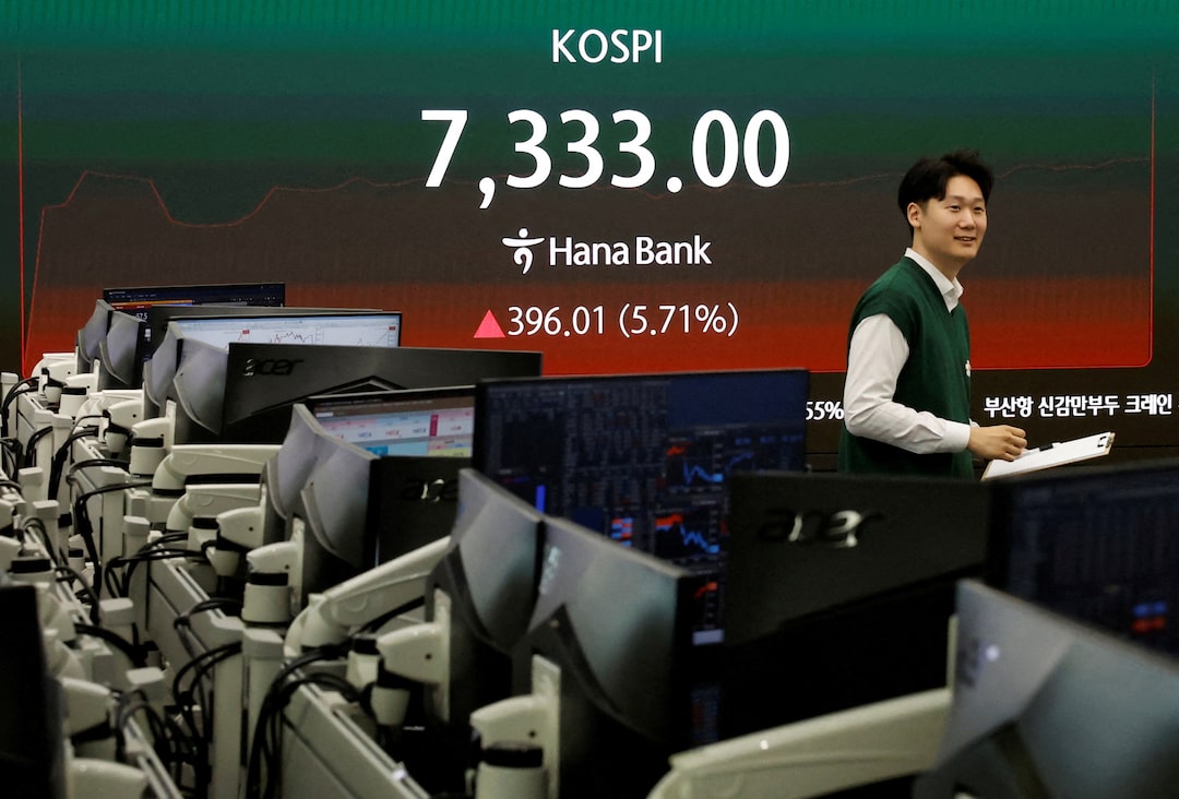 A currency dealer looks on as a KOSPI board opens above 7,000 in Seoul.