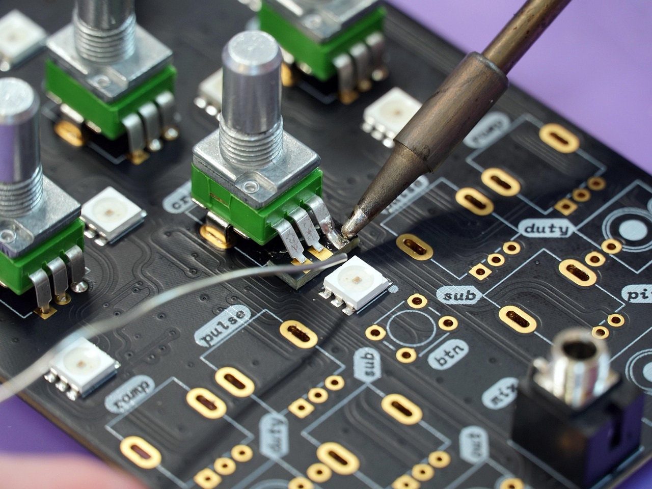 Soldering equipment over a circuit board, representing semiconductor manufacturing constraints.