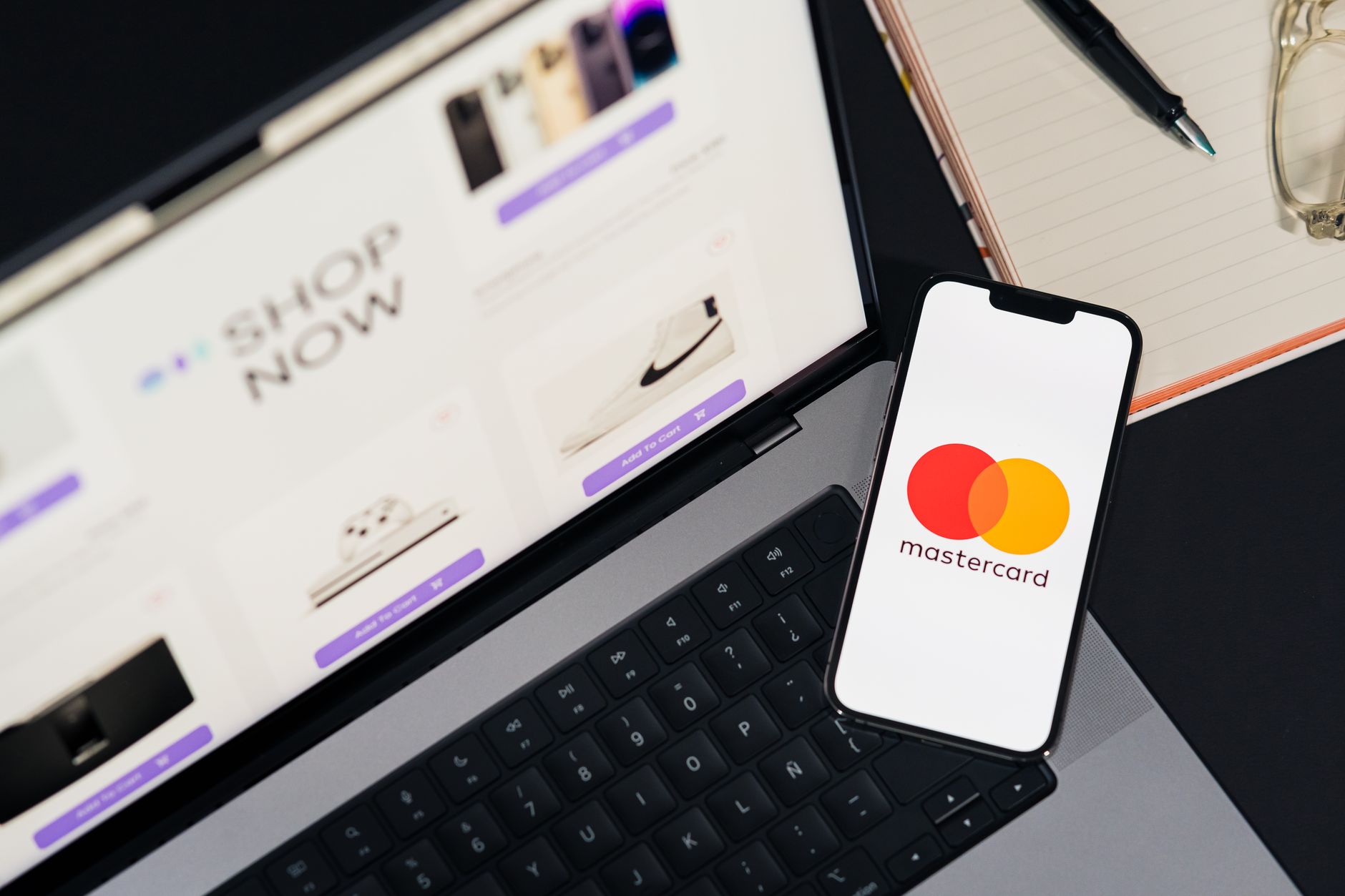 Laptop and smartphone with a Mastercard logo, illustrating digital payments and card settlement.