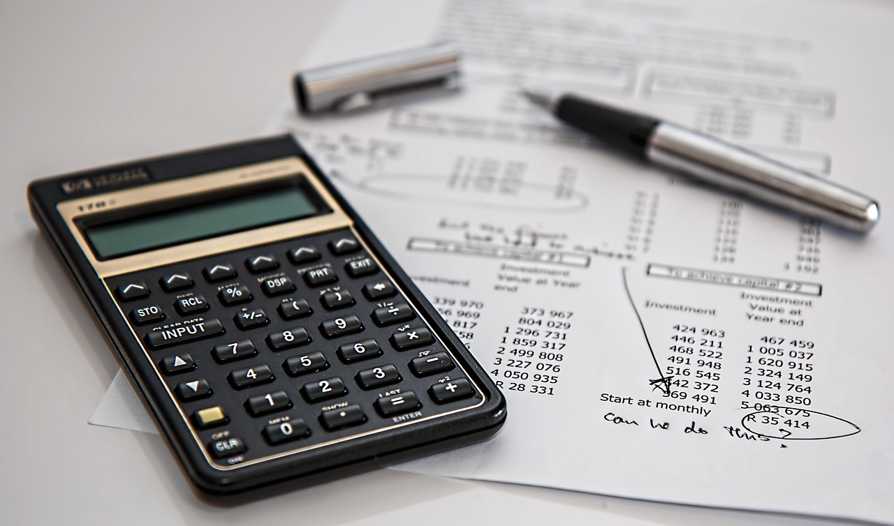 Calculator, paperwork and pen representing student-loan repayment choices