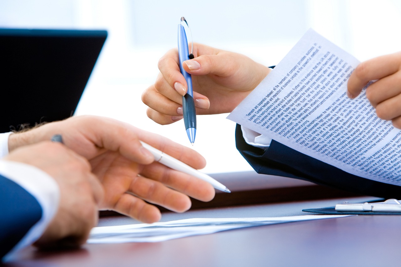 Hands review financial paperwork beside a laptop, reflecting borrower forms and account updates.