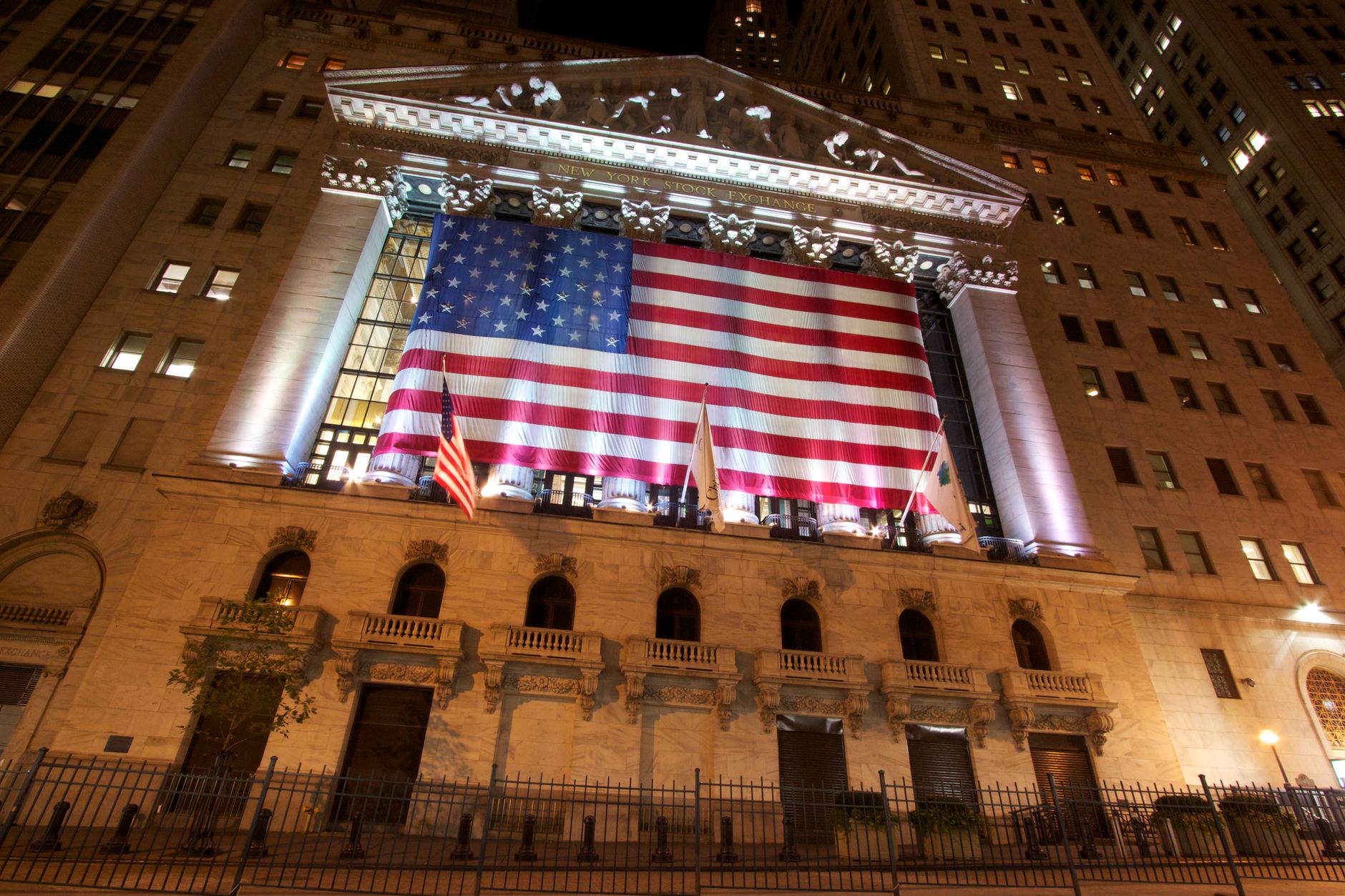 New York Stock Exchange facade at night with American flag