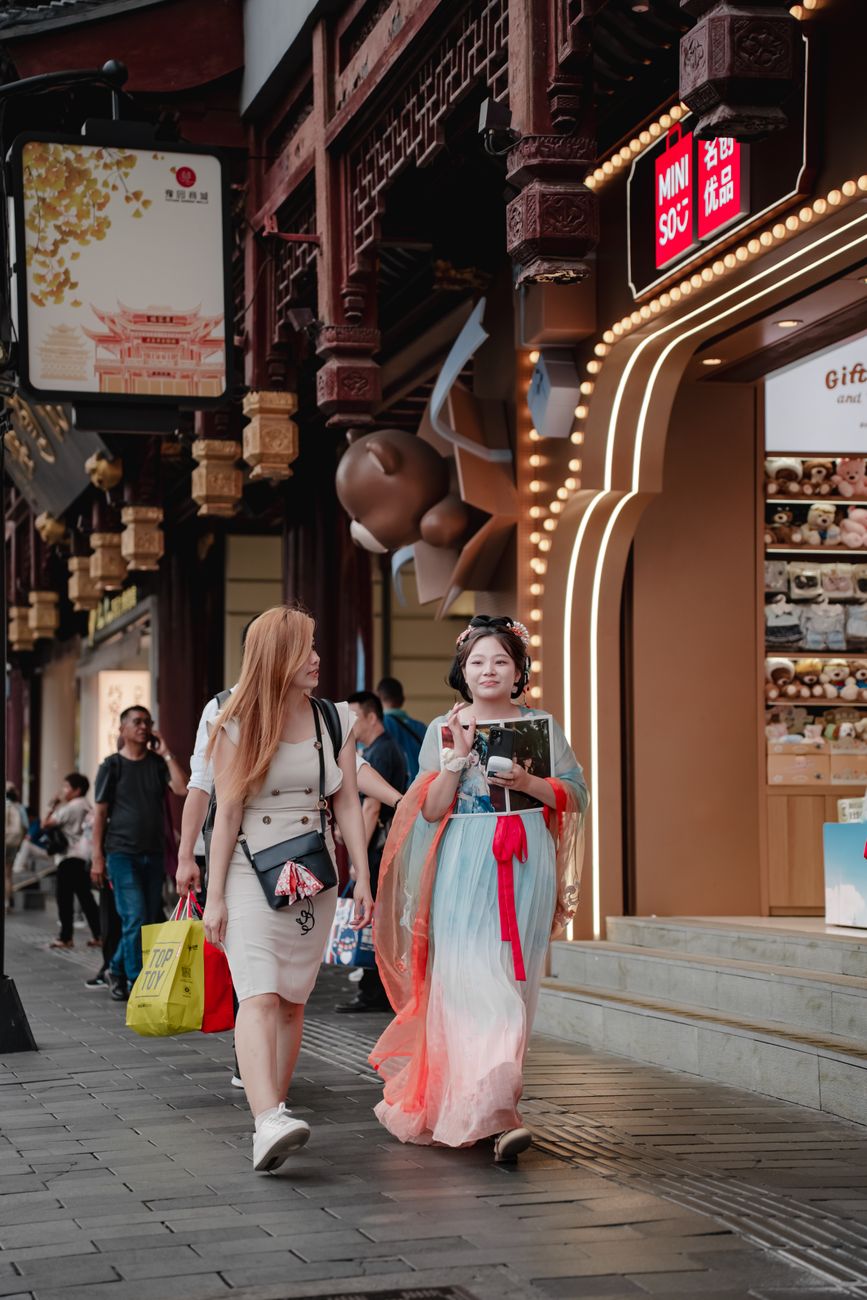 Shoppers move through a Chinese outdoor market as retail data point to weaker consumer demand.