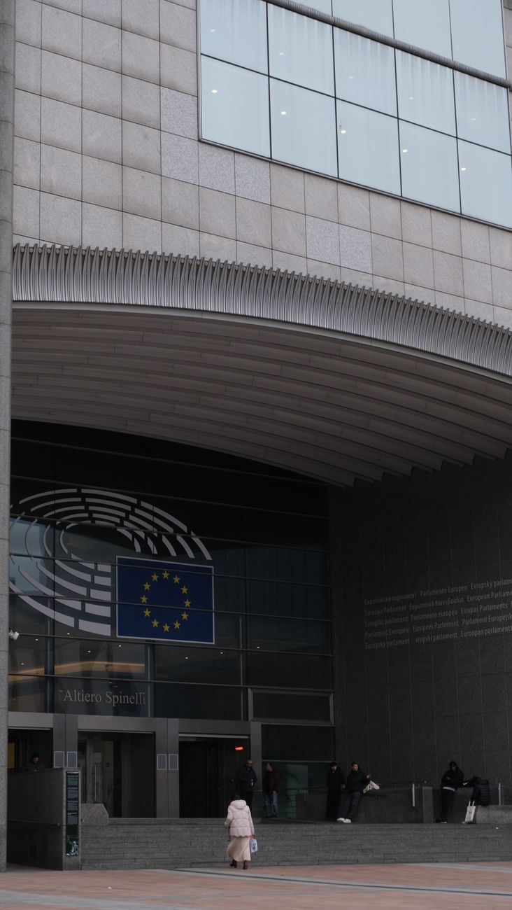 Entrance of European Parliament building in Brussels showcasing modern architecture and EU flag.