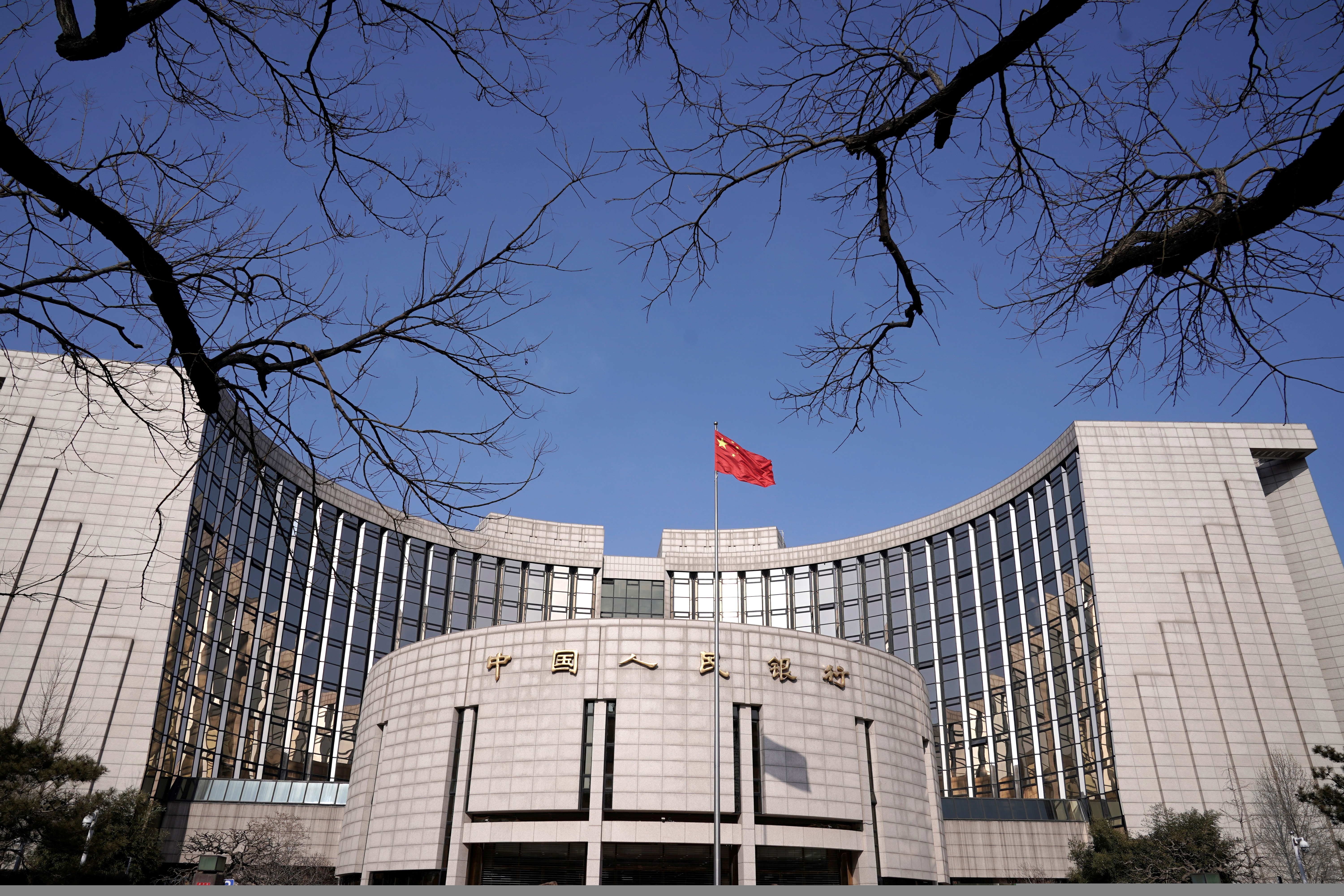 A fluttering Chinese national flag casts its shadow on the headquarters of the People's Bank of China, China's central bank, in central Beijing.
