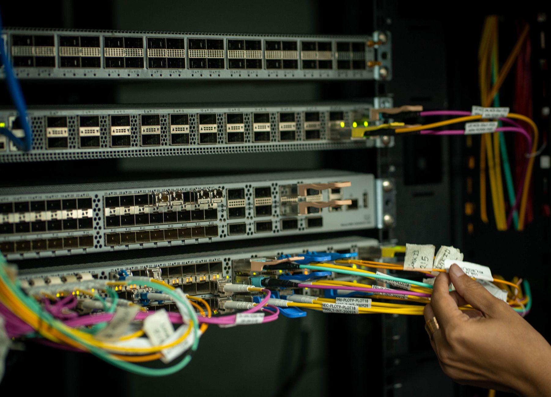 Engineer handling fiber-optic cables in a data center