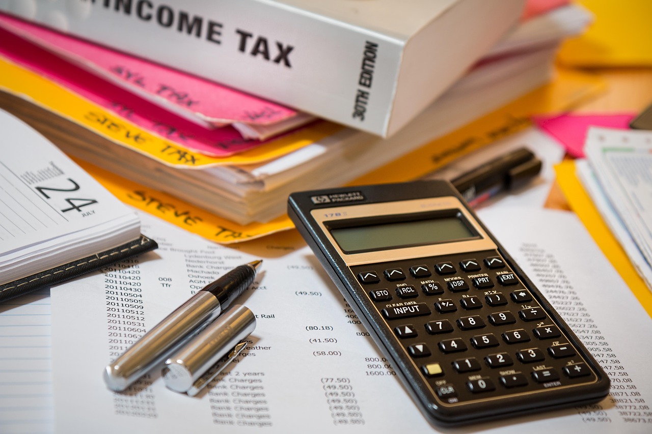 Calculator, tax forms and paperwork on a desk as borrowers compare federal repayment options.