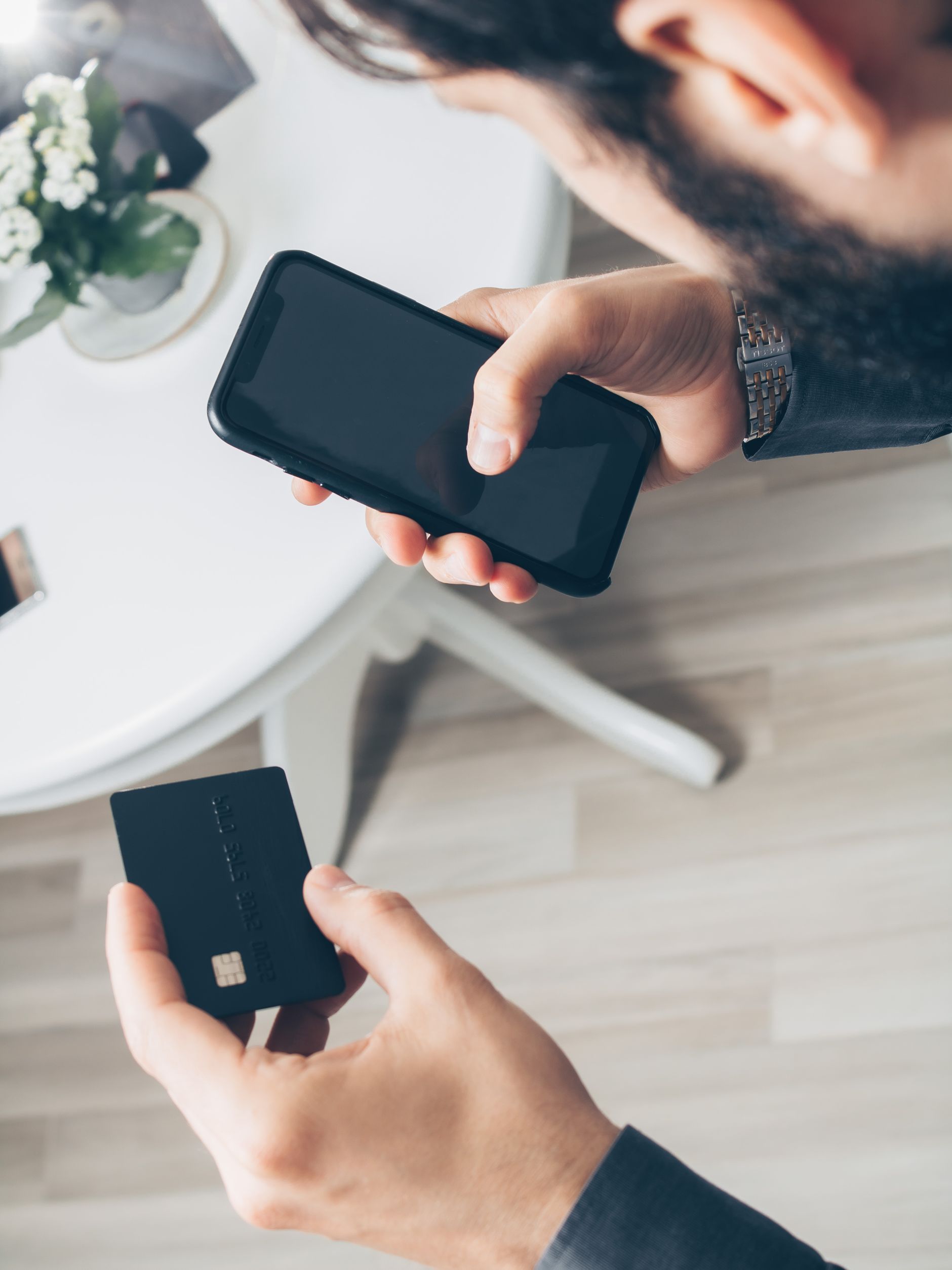 A customer uses a smartphone and bank card for a digital payment, illustrating fintech payment rails and online banking access.